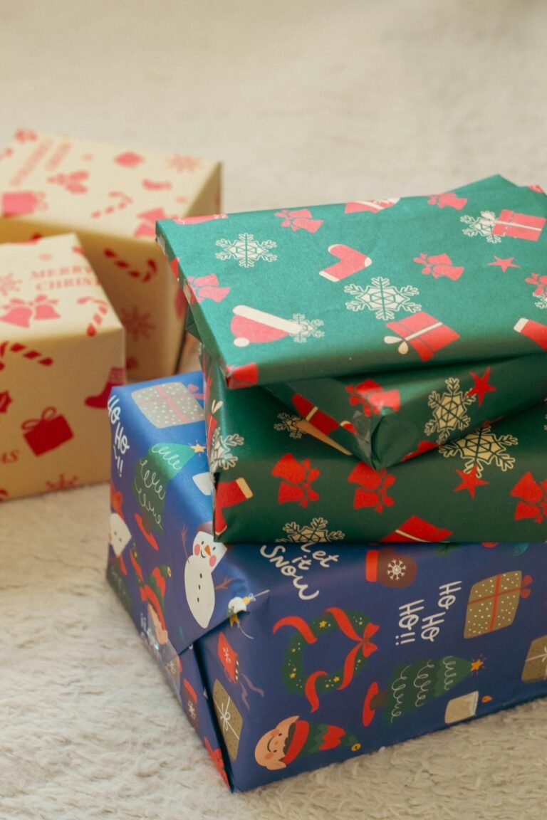 Stack of colorful Christmas gift boxes with festive wrapping paper featuring snowflakes, Santa, and stockings.